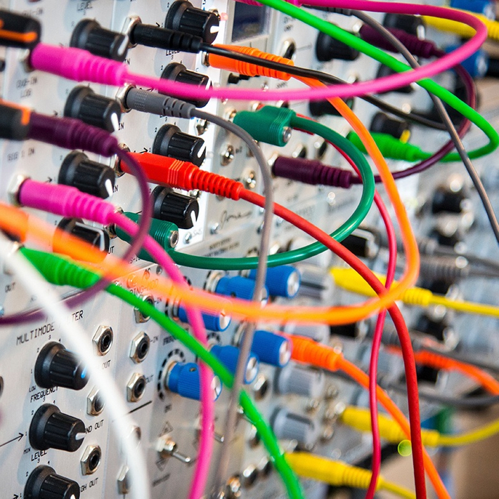 Viele verschiedenfarbige Kabel, die mit einem Server verbunden sind, an dem zusätzlich Regler befestigt sind.